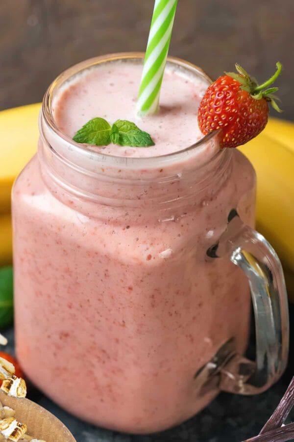 NutriBullet Strawberry Cupcake smoothie in a glass, on my kitchen counter, surrounded by fresh fruit.
