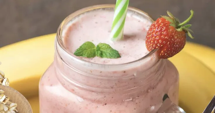 NutriBullet Strawberry Cupcake smoothie in a glass, on my kitchen counter, surrounded by fresh fruit.