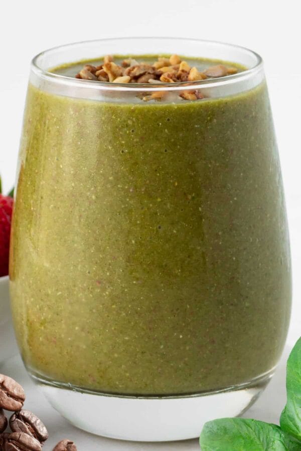 NutriBullet Superfood Coffee Boost smoothie in a glass, on my kitchen counter, surrounded by coffee beans and vegetables.