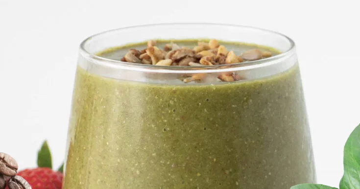 NutriBullet Superfood Coffee Boost smoothie in a glass, on my kitchen counter, surrounded by coffee beans and vegetables.