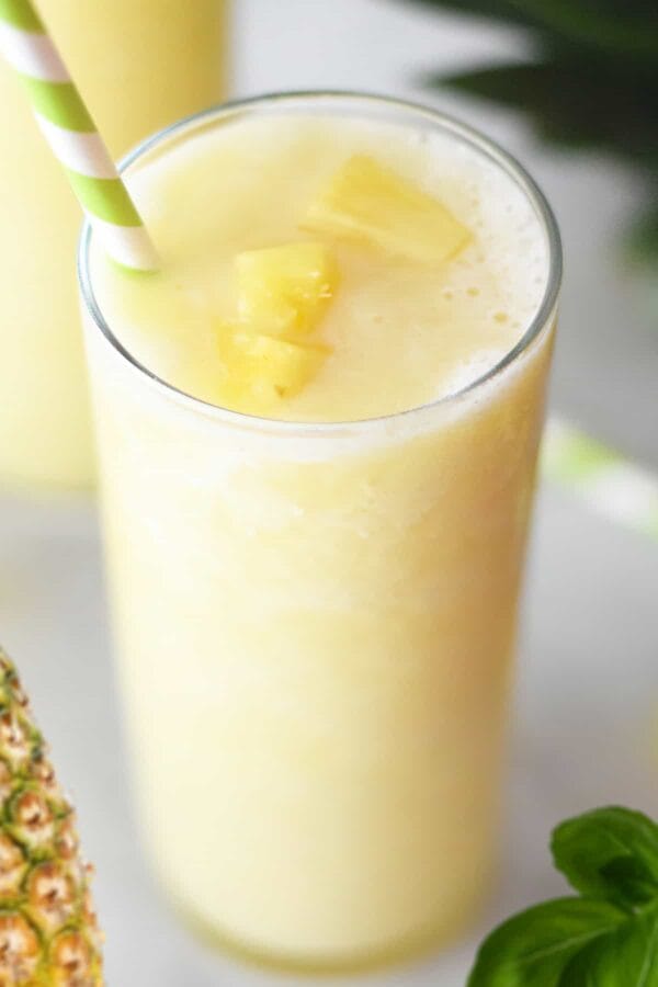 NutriBullet Tropical Pineapple Basil smoothie in a glass, on my kitchen counter, surrounded by fresh fruit.