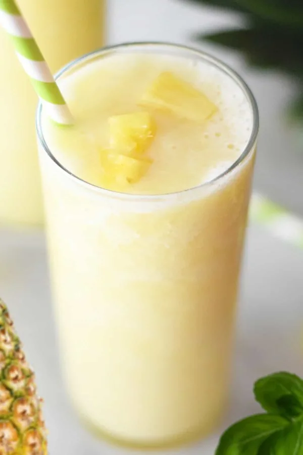 NutriBullet Tropical Pineapple Basil smoothie in a glass, on my kitchen counter, surrounded by fresh fruit.
