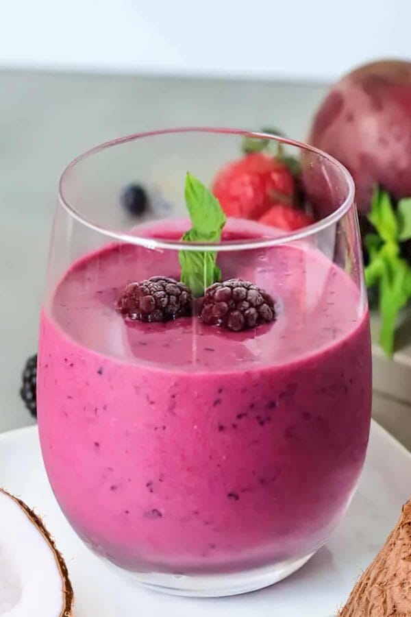 NutriBullet Very Merry Valentine smoothie in a glass, on my kitchen counter, surrounded by fresh fruit.