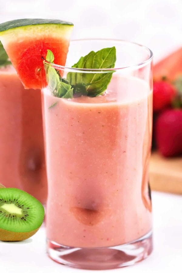 NutriBullet Watermelon Kiwi Nectar smoothie in a glass, on my kitchen counter, surrounded by fresh fruit.