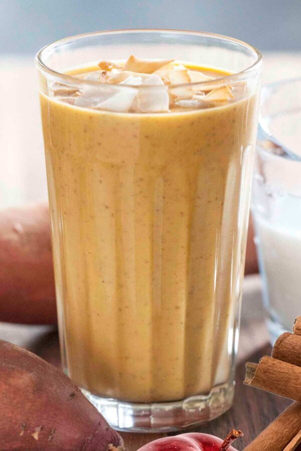NutriBullet Wintertime Warrior smoothie in a glass, on my kitchen counter, surrounded by fresh fruit and vegetables.