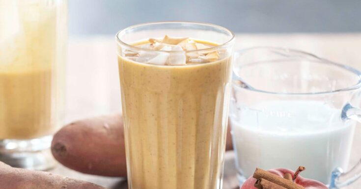 NutriBullet Wintertime Warrior smoothie in a glass, on my kitchen counter, surrounded by fresh fruit and vegetables.