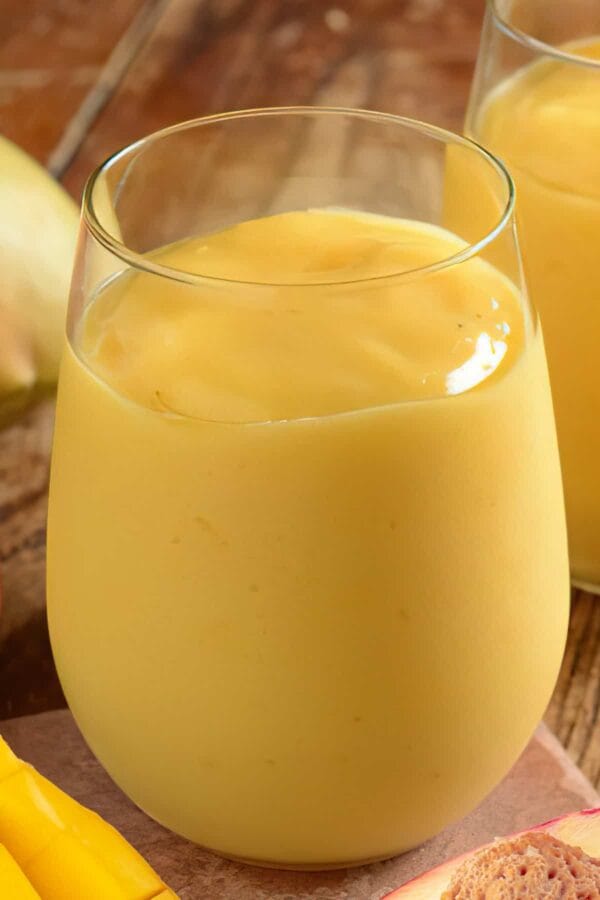 NutriBullet Zingy Orange Peach Mango smoothie in a glass, on my kitchen counter, surrounded by fresh fruit.