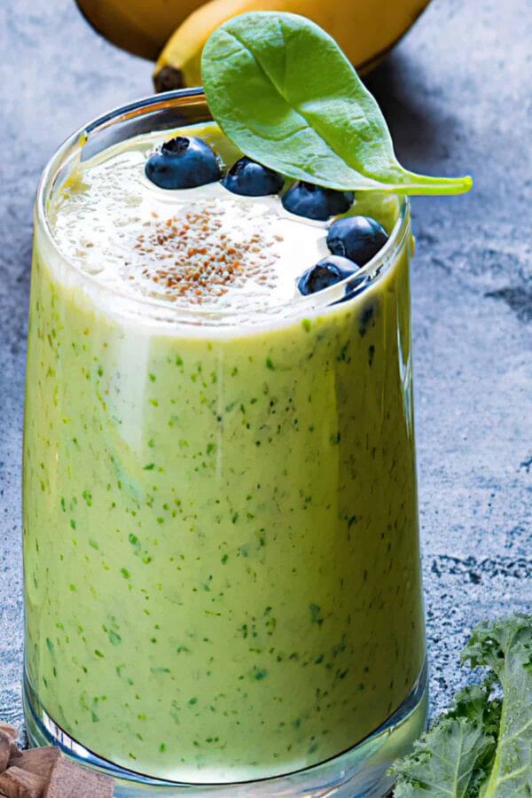 NutriBullet Cholesterol Crusher Blast smoothie in a glass, on my kitchen counter, surrounded by fresh fruit and vegetables.