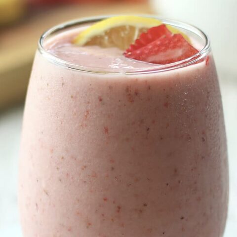 NutriBullet Pink Drink smoothie in a glass, on my kitchen counter, surrounded by fresh fruit.
