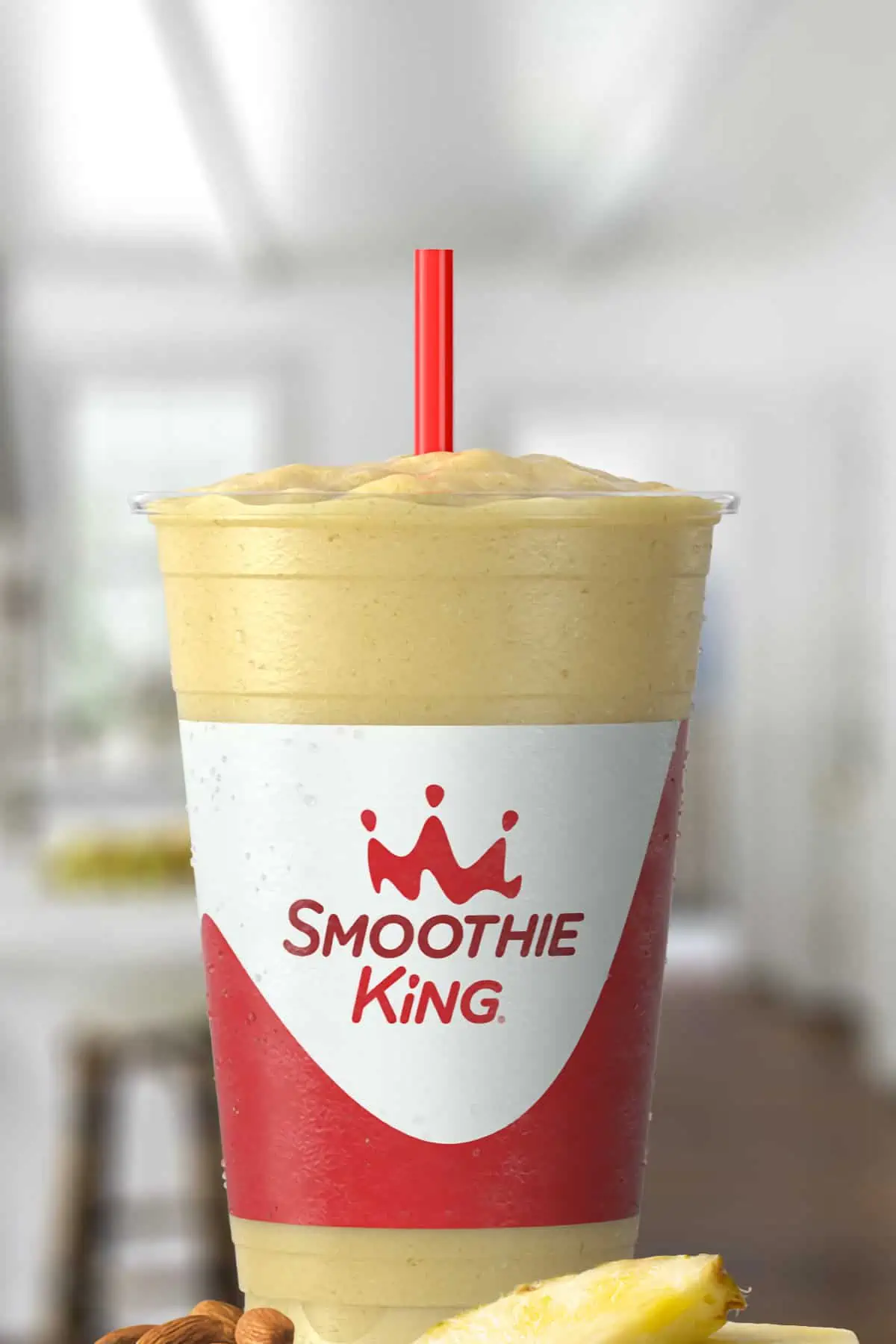 Smoothie King Original High Protein Pineapple smoothie in a glass, on my kitchen counter, surrounded by fresh fruit.