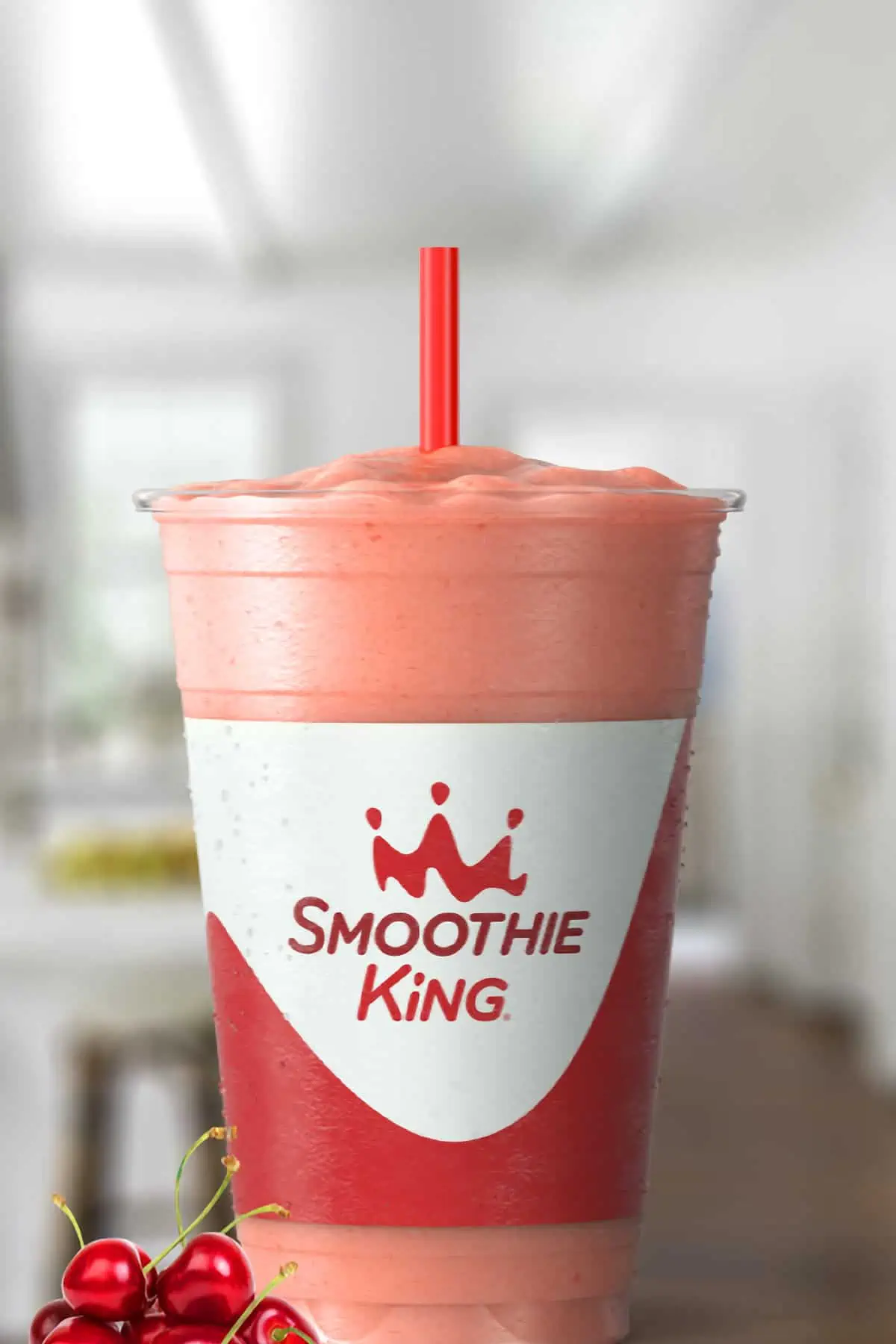 Smoothie King Stretch And Flex Tart Cherry smoothie in a glass, on my kitchen counter, surrounded by fresh fruit.
