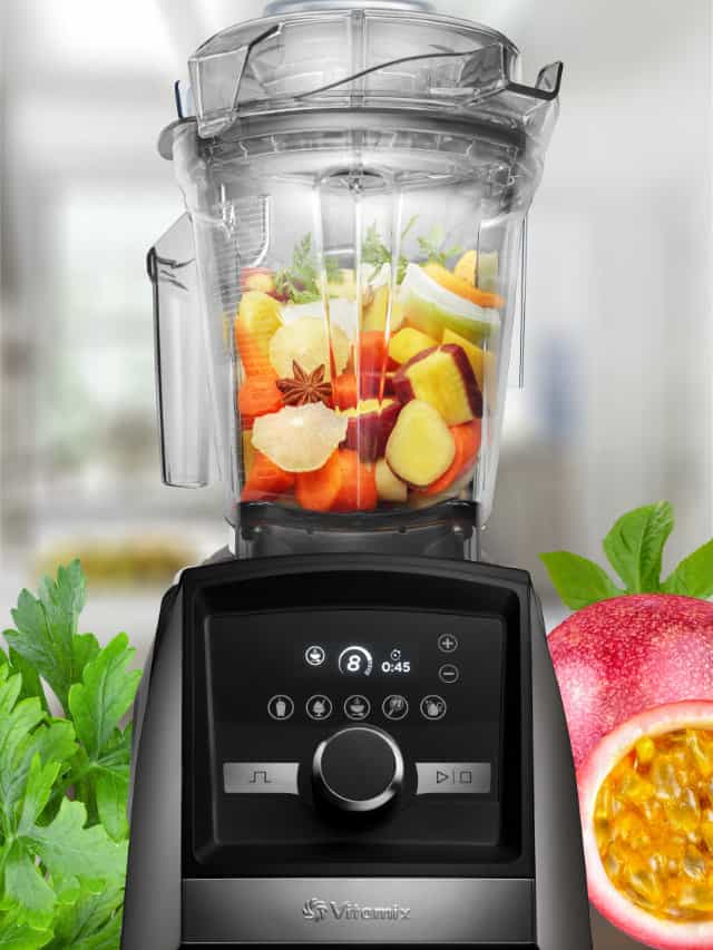 Vitamix blender blending a Vitamix smoothie, on my kitchen counter, surrounded by fresh fruit and vegetables.