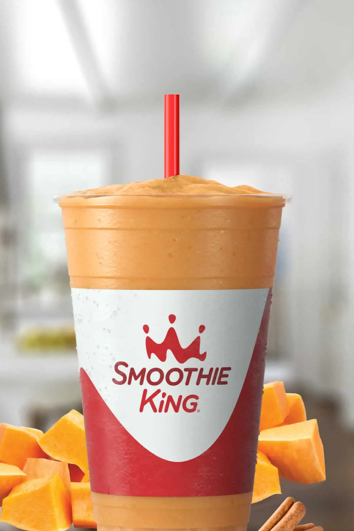 Smoothie King Pumpkin D-Lite smoothie in a glass, on my kitchen counter, surrounded by fresh fruit.