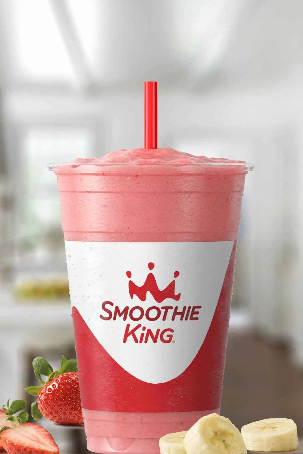 Smoothie King Angel Food smoothie in a glass, on my kitchen counter, surrounded by fresh fruit and vanilla.