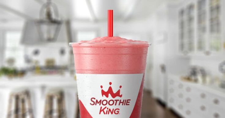 Smoothie King Angel Food smoothie in a glass, on my kitchen counter, surrounded by fresh fruit and vanilla.