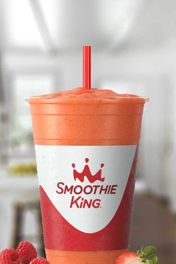 Smoothie King Kids Berry Interesting smoothie in a glass, on my kitchen counter, surrounded by fresh berries.