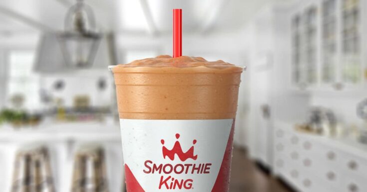 Smoothie King Kids Choc-A-Laka smoothie in a glass, on my kitchen counter, surrounded by dates and cacao powder.