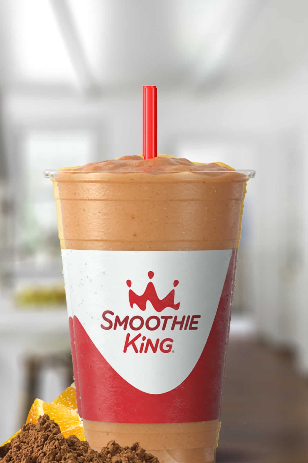 Smoothie King Kids Choc-A-Laka smoothie in a glass, on my kitchen counter, surrounded by dates and cacao powder.