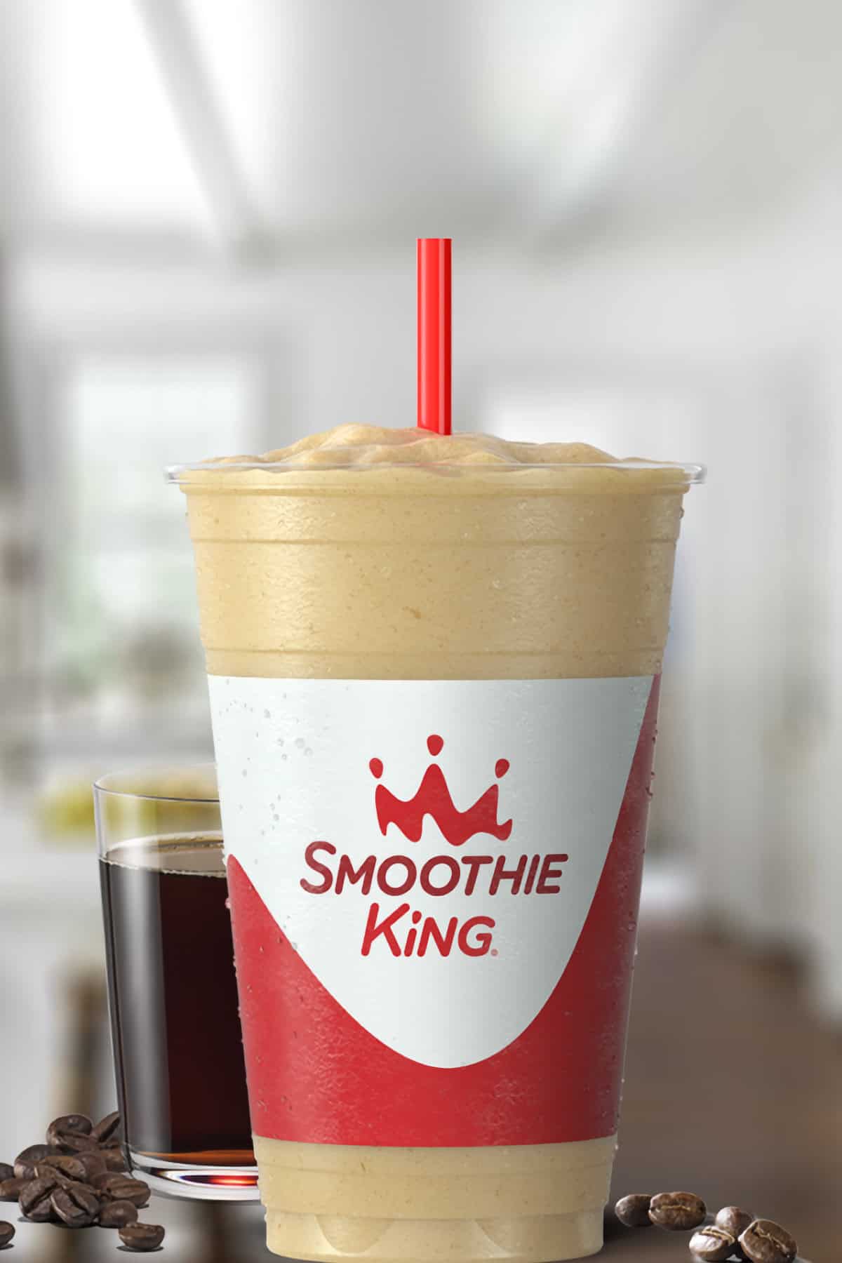 Smoothie King Coffee D-Lite Vanilla smoothie in a glass, on my kitchen counter, surrounded by coffee beans.