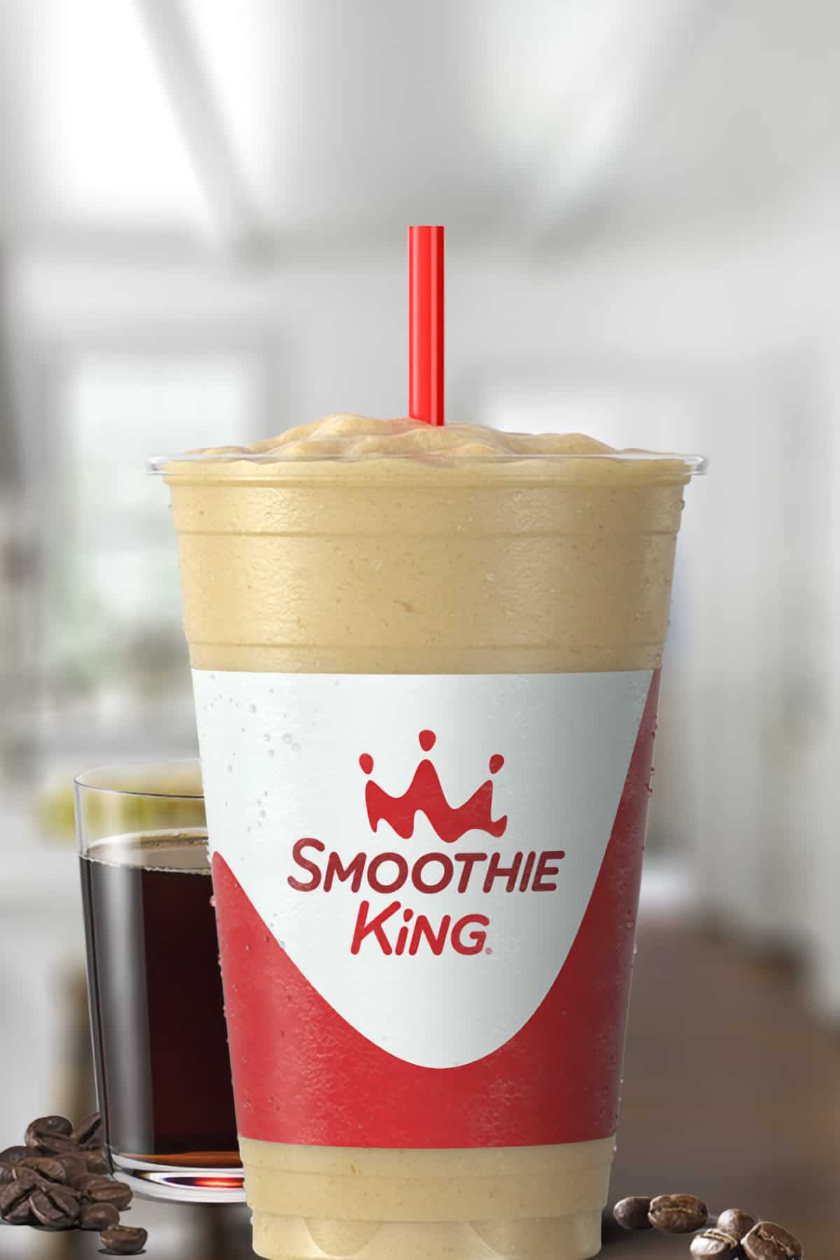 Smoothie King Espresso D-Lite Vanilla smoothie in a glass, on my kitchen counter, surrounded by coffee beans.