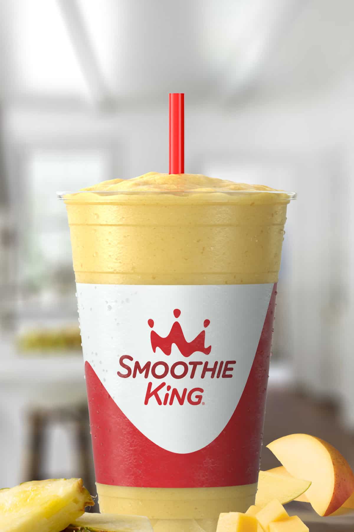 Smoothie King Lean1 Pineapple Mango smoothie in a glass, on my kitchen counter, surrounded by pineapple slices and mango.