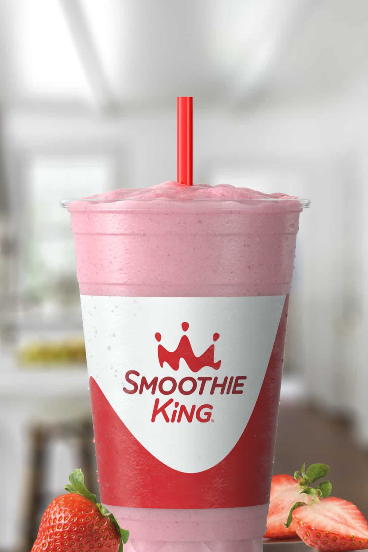 Smoothie King Lean1 Strawberry smoothie in a glass, on my kitchen counter, surrounded by fresh strawberries.