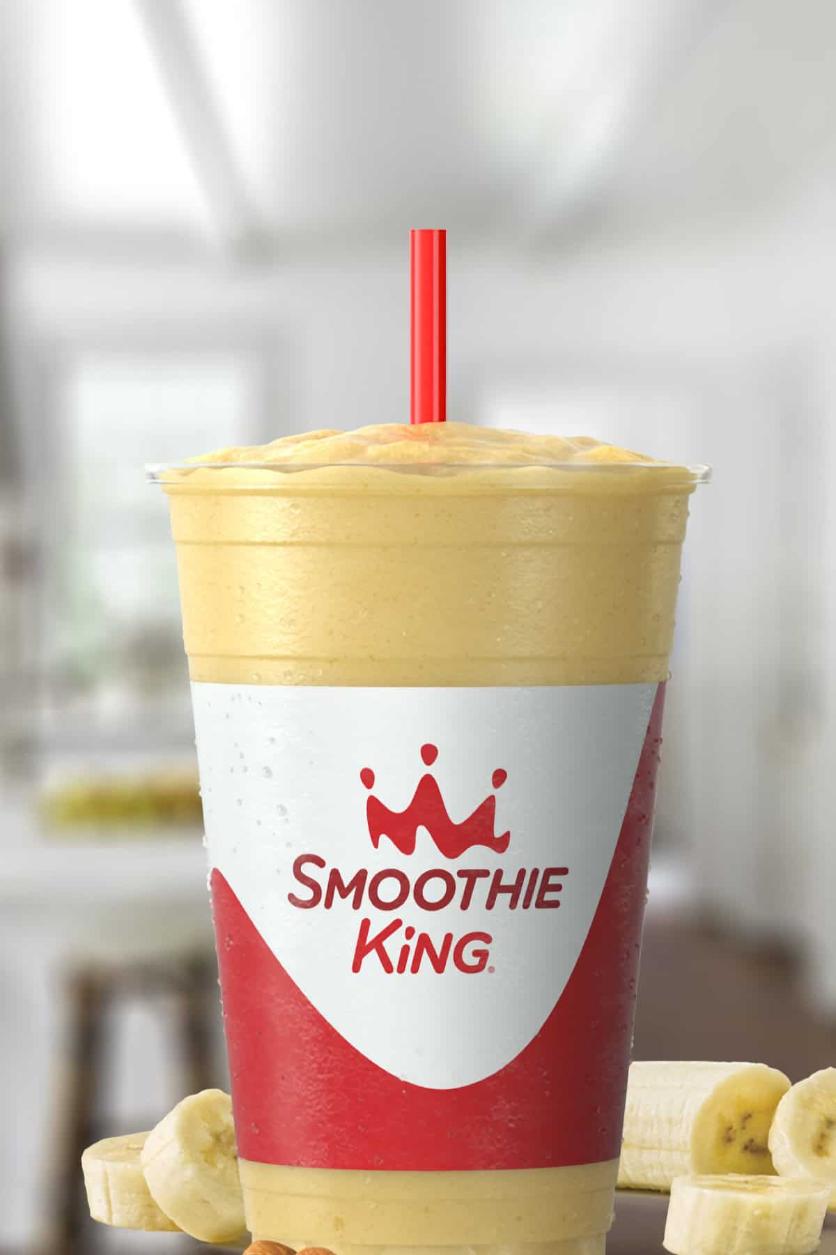 Smoothie King Lean1 Vanilla smoothie in a glass, on my kitchen counter, surrounded by sliced bananas.