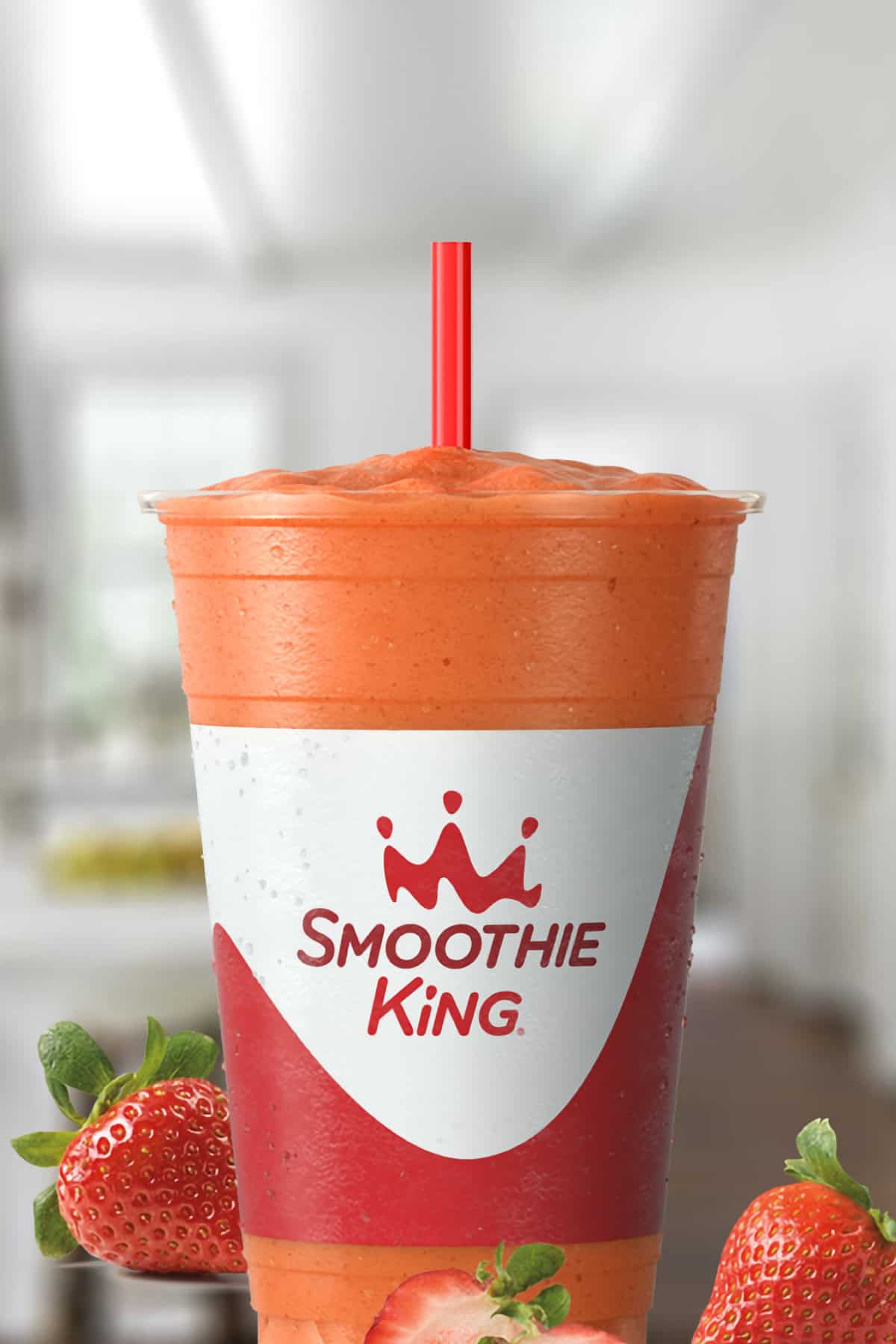 Smoothie King Lemon Twist Strawberry smoothie in a glass, on my kitchen counter, surrounded by fresh strawberries.