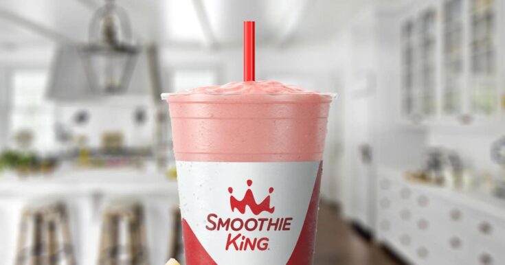 Smoothie King Metabolism Boost Strawberry Pineapple smoothie in a glass, on my kitchen counter, surrounded by fresh strawberries and pineapple slices.