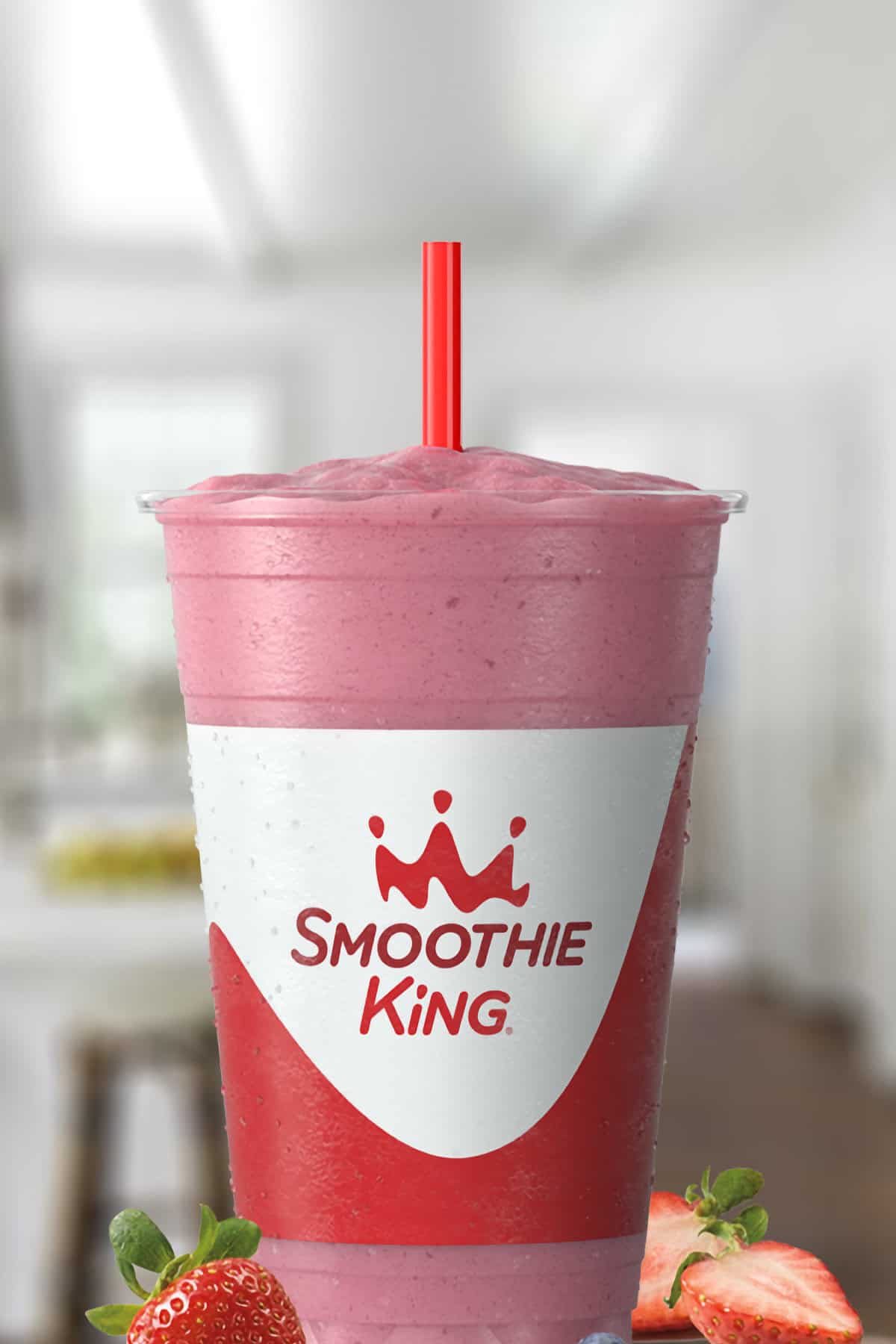 Smoothie King The Activator Recovery Blueberry Strawberry smoothie in a glass, on my kitchen counter, surrounded by fresh strawberries.