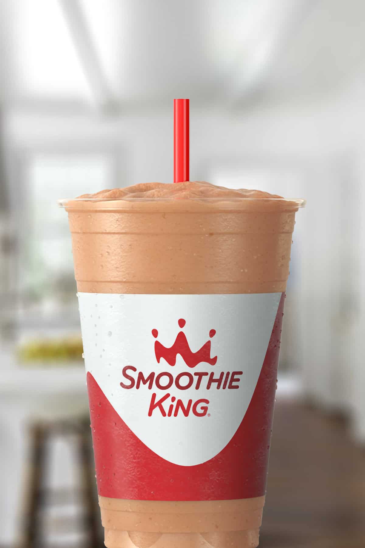 Smoothie King Yogurt D-Lite smoothie in a glass, on my kitchen counter, surrounded by nonfat frozen yogurt.