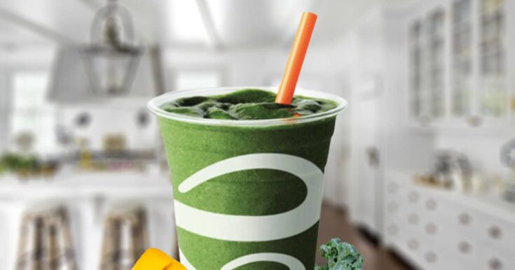 Jamba Juice The Go Getter smoothie in a glass, on my kitchen counter, surrounded by fresh mango and kale.