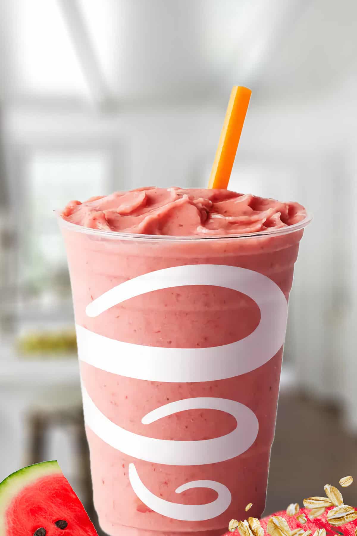 Jamba Juice Watermelon Breeze Dairy Free smoothie in a glass, on my kitchen counter, surrounded by fresh watermelon and oats.