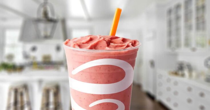 Jamba Juice Watermelon Breeze smoothie in a glass, on my kitchen counter, surrounded by fresh watermelon.