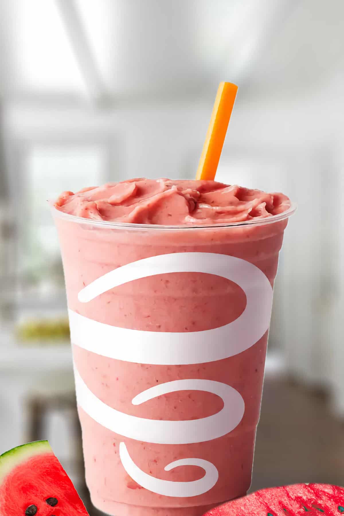 Jamba Juice Watermelon Breeze smoothie in a glass, on my kitchen counter, surrounded by fresh watermelon.