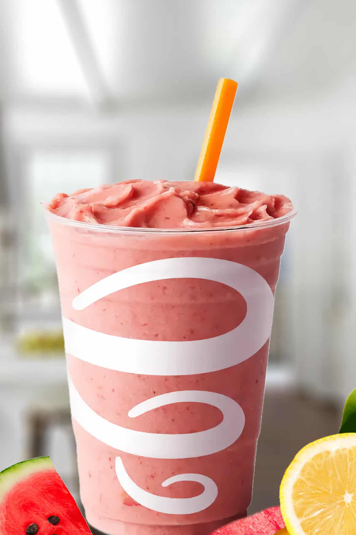 Jamba Juice Watermelon Lemonade smoothie in a glass, on my kitchen counter, surrounded by fresh watermelon and lemon slices.