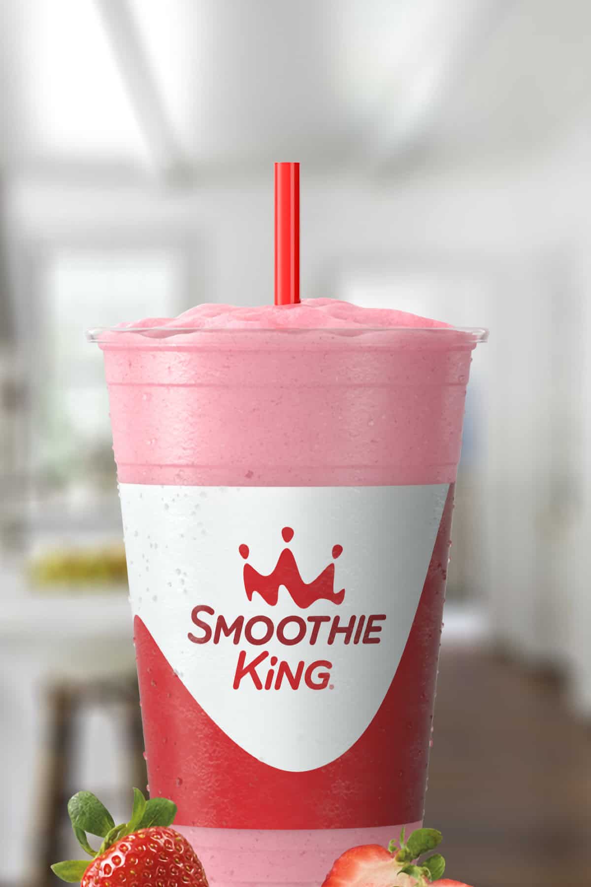 Smoothie King Power Slim Strawberry smoothie in a glass, on my kitchen counter, surrounded by fresh strawberries.