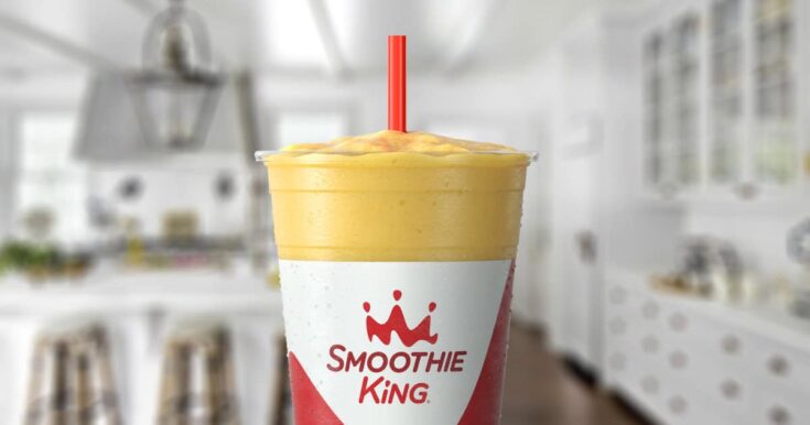 Smoothie King Power Slim Vanilla smoothie in a glass, on my kitchen counter, surrounded by sliced bananas.