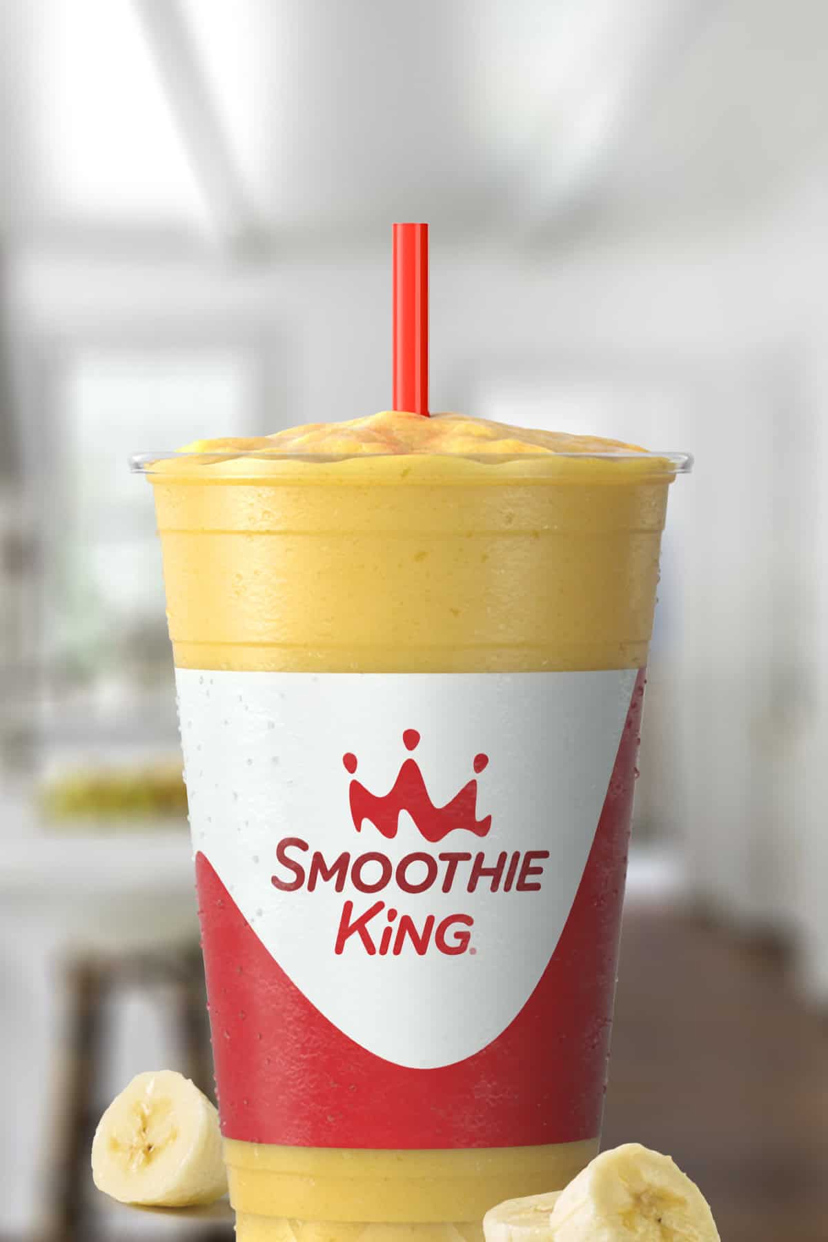 Smoothie King Power Slim Vanilla smoothie in a glass, on my kitchen counter, surrounded by sliced bananas.