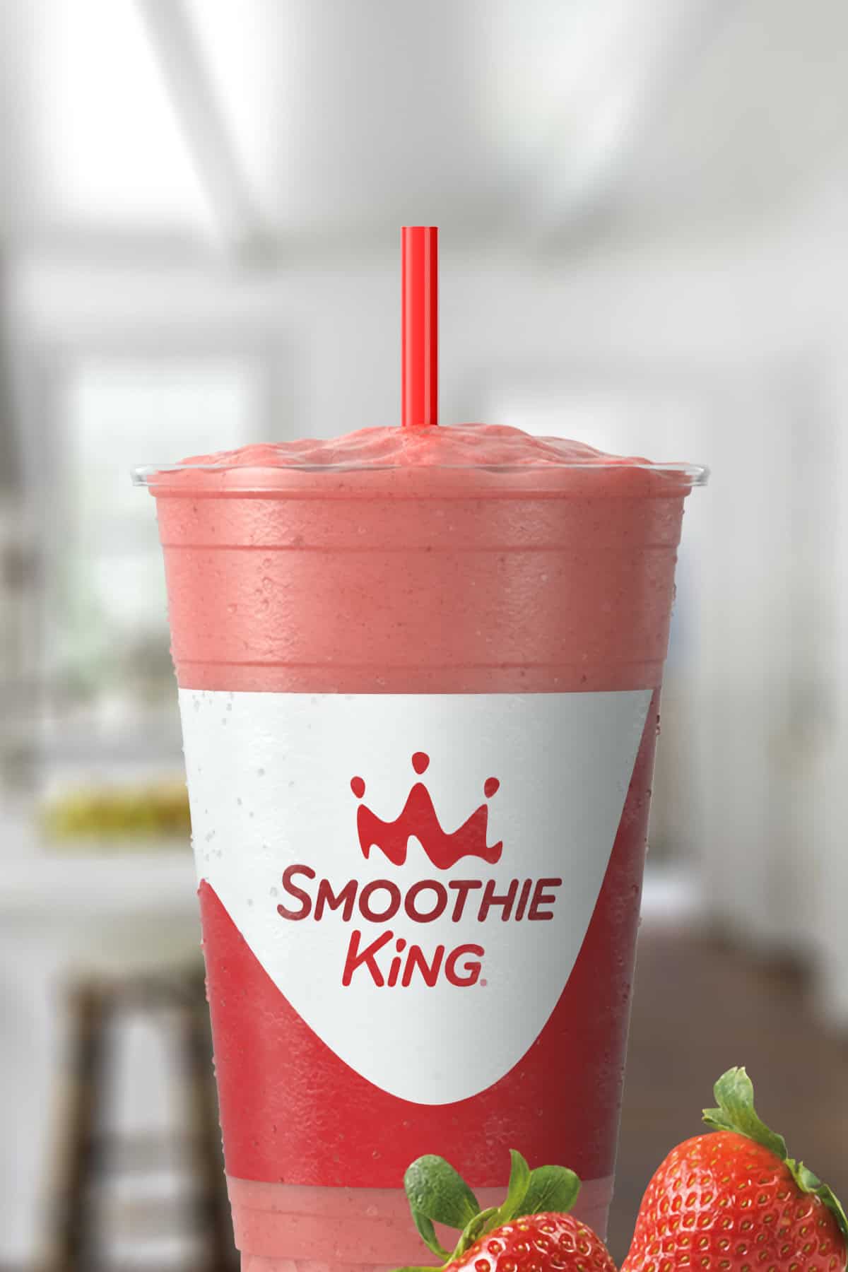 Smoothie King Slim-N-Trim Strawberry smoothie in a glass, on my kitchen counter, surrounded by fresh strawberries.