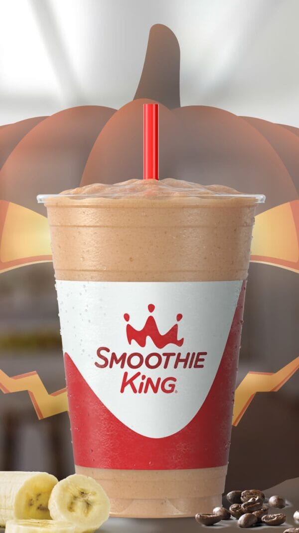 Monster's Brew Halloween smoothie in a glass, on my kitchen counter, surrounded by bananas and coffee beans.