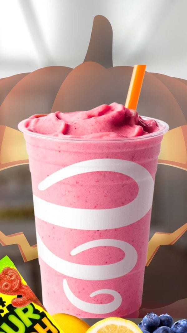 Sour Patch Kids Halloween smoothie in a glass, on my kitchen counter, surrounded by Halloween candy.