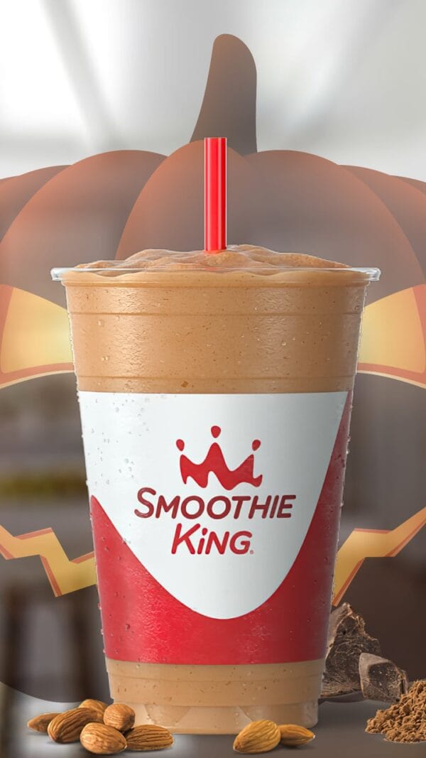 Witch's Brew Mocha Halloween smoothie in a glass, on my kitchen counter, surrounded by almonds and cacao powder.